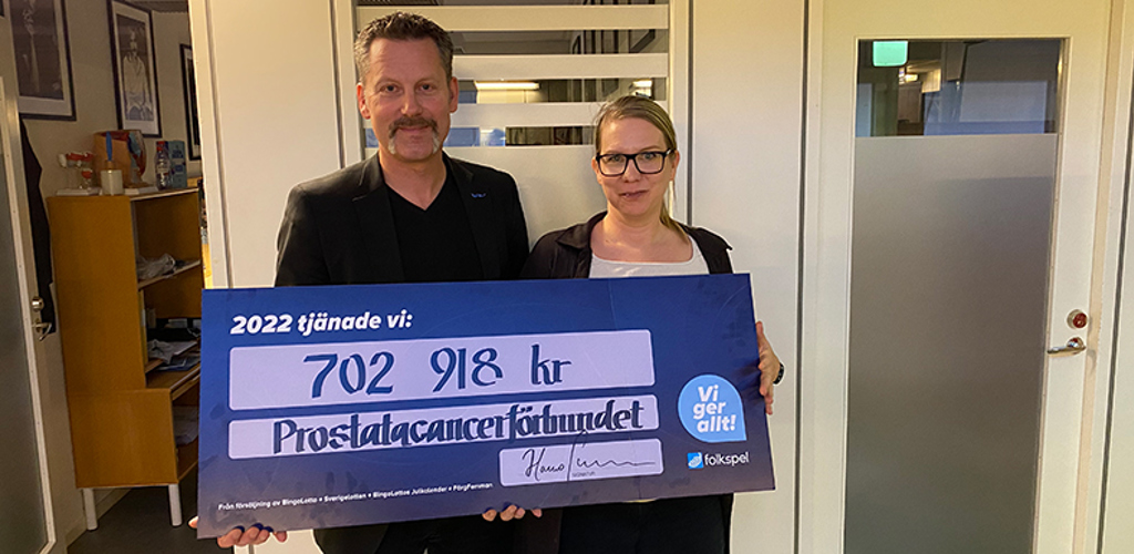 Per-Anders Nygård och Maria Ahlvik från Prostatacancerförbundet håller upp en check motsvarande utdelningen från Folkspel 2022.