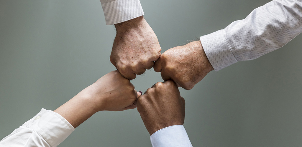 Närbild på fyra knytna nävar som bildar en kvadrat