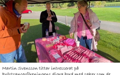 Martin Svensson tittar intresserat på Bröstcancerföreningens digra bord med saker de sålde för att samla in pengar till förmån för drabbade. Titti i mitten och Cissi till höger.