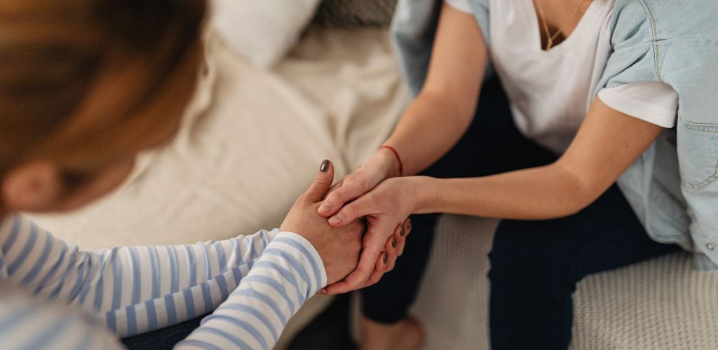Bild på två personer som håller hand och visar omtanke.