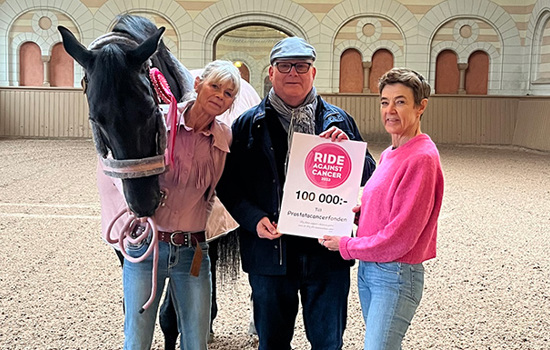 Man tar emot en check från två kvinnor som står tillsammans med en häst