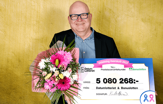 Prostatacancerförbundets generalsekreterare Olov Berggren håller i en check från Datumlotteriet och en stor blomsterbukett.
