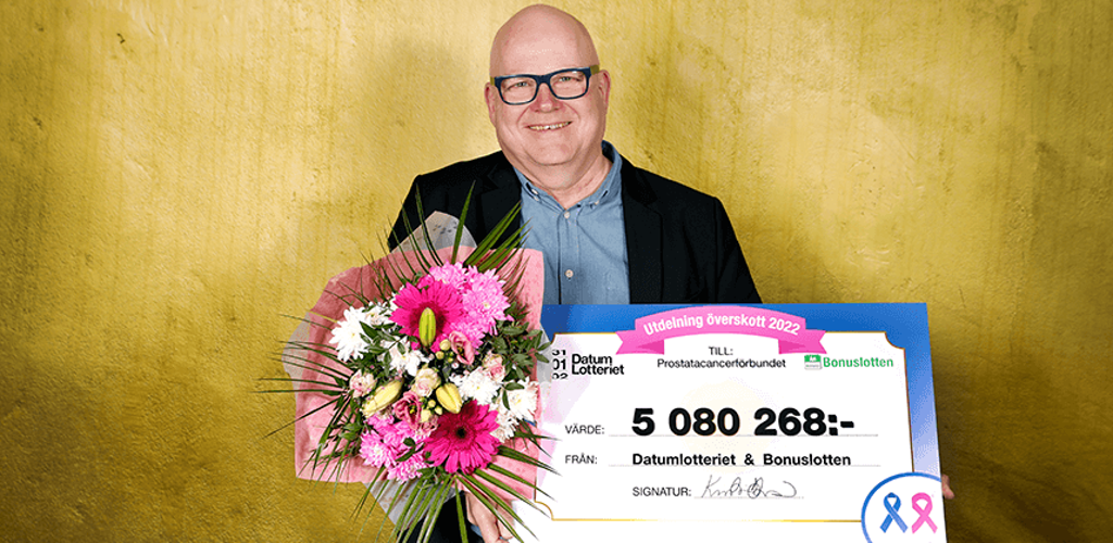 Prostatacancerförbundets generalsekreterare Olov Berggren håller i en check från Datumlotteriet och en stor blomsterbukett.