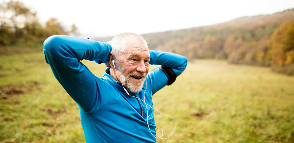 Äldre man som tränar utomhus med hörlurar i öronen