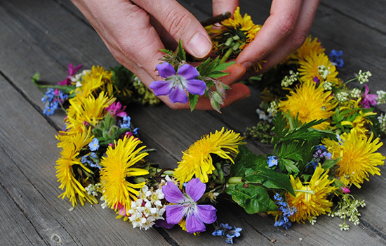 Händer som håller i en blomstrande midsommarkrans