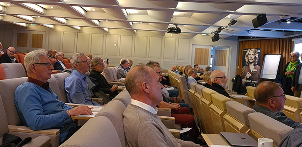 Vy över personer som lyssnar på ett föredrag i en stor konferenssal