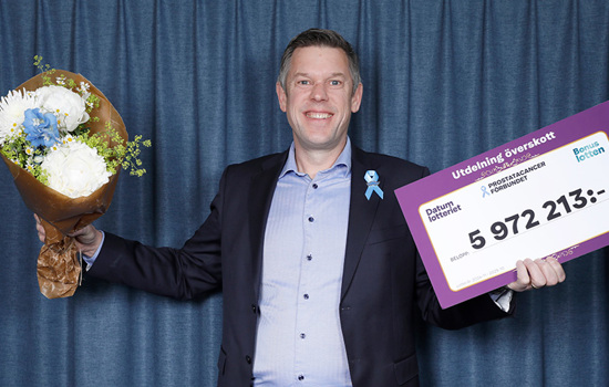 Glad man med en blombukett i ena handen och en check i den andra handen 